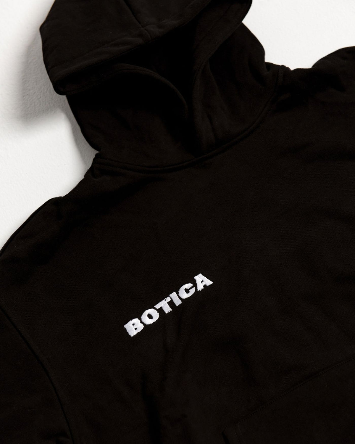 Close-up of the raised puff print BOTICA chest logo on the black Legacy Hoodie